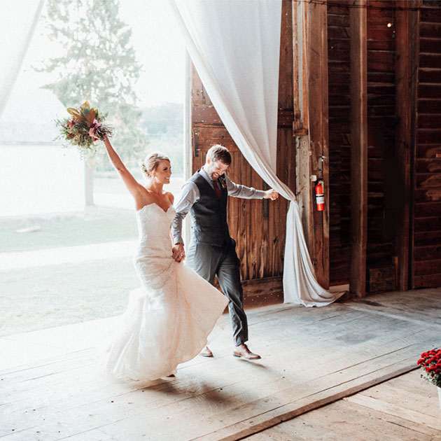 Newlyweds walking out of a rustic barn at a Pennsylvania wedding expo.