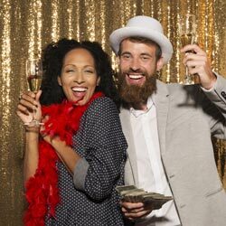 A couple posing in front of a gold photo booth at a Pennsylvania wedding expo.